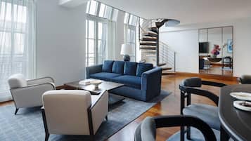 A modern living room with a blue sofa, a coffee table, and a dining area with a table and chairs.