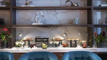 A modern dining area with marble countertops, blue chairs, and a variety of food and drink items displayed on the table.