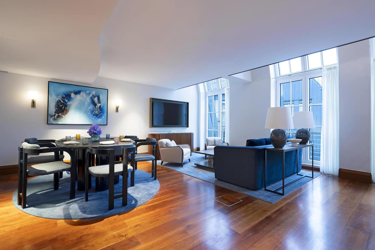 A modern living room with a dining area, a large window, and a flat-screen TV.