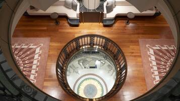 A grand staircase with a glass railing, leading to a seating area with a marble floor and a central sunburst design.