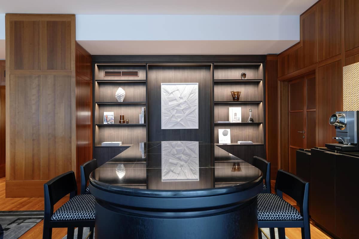 A modern dining area with a round table, black chairs, and wooden paneling.