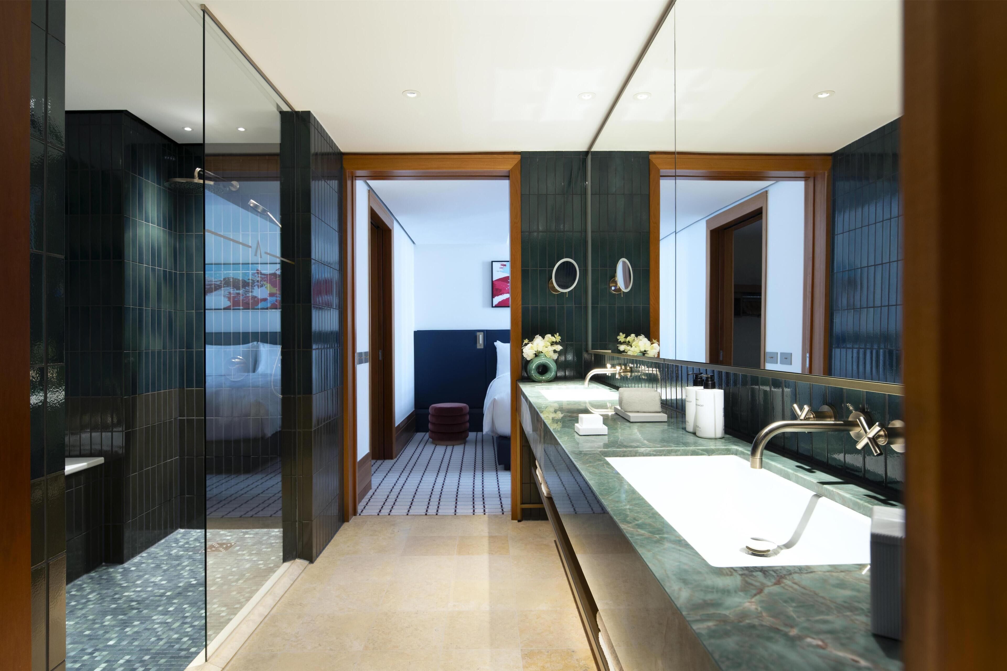 A modern bathroom with a large mirror, a marble countertop, and a glass shower enclosure.