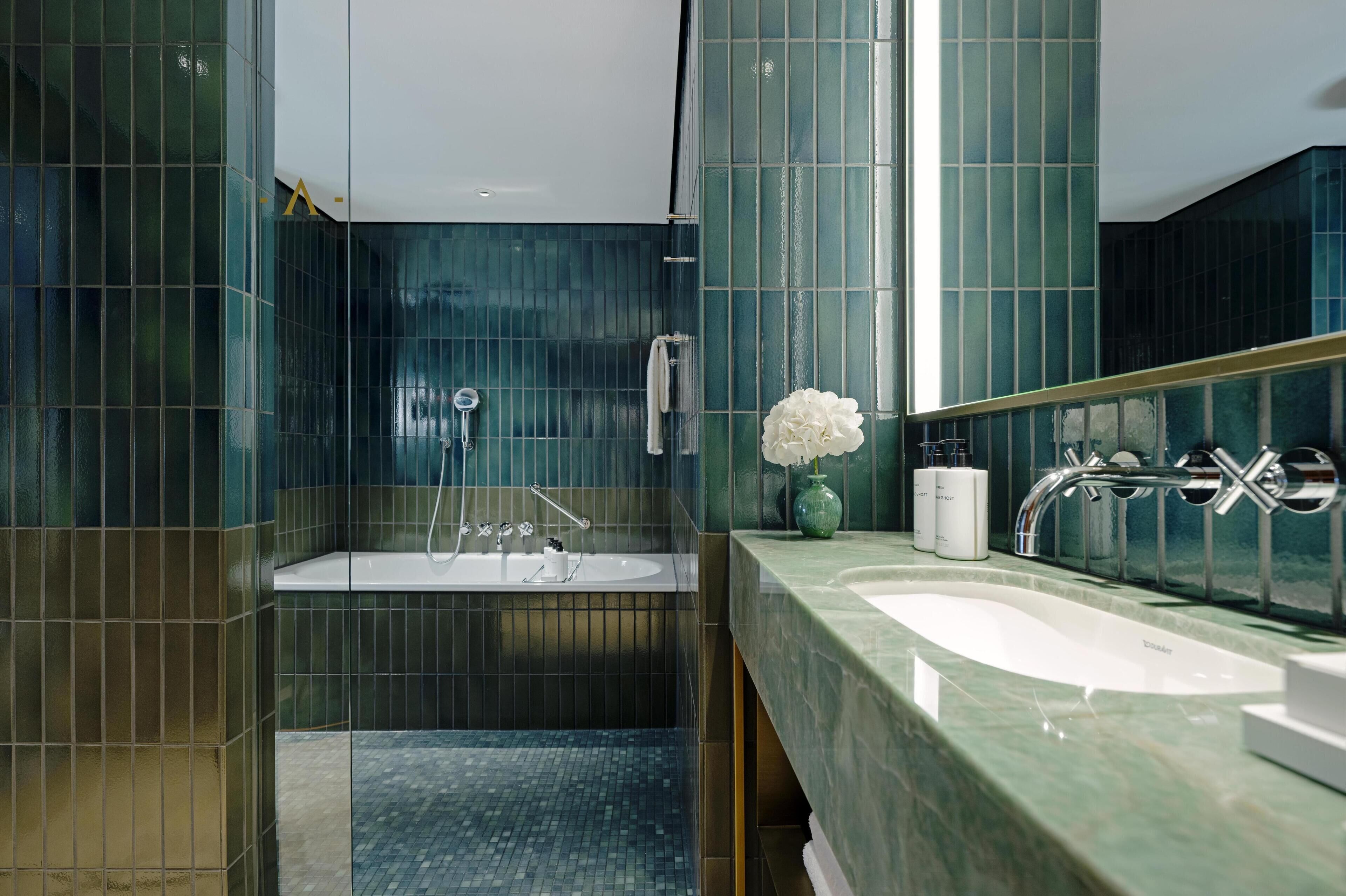A modern bathroom with a large mirror, two sinks, and a bathtub.