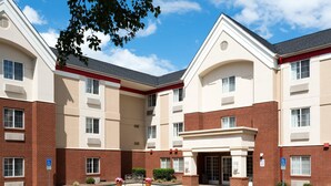A multi-story hotel with a central courtyard, brick and beige exterior, and handicap-accessible parking. - MainStay Suites Raleigh - Cary (Cary)
