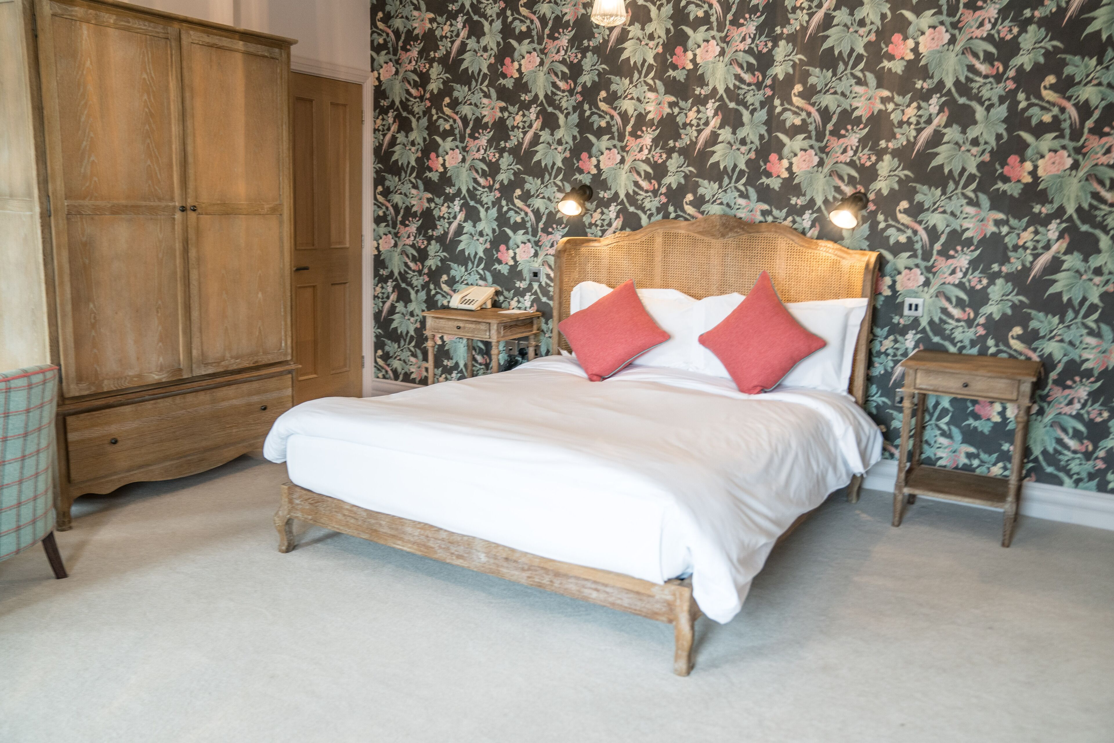 Un dormitorio con cama de madera, papel tapiz floral y un armario.