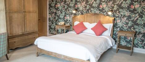 Un dormitorio con cama de madera, papel tapiz floral y un armario.