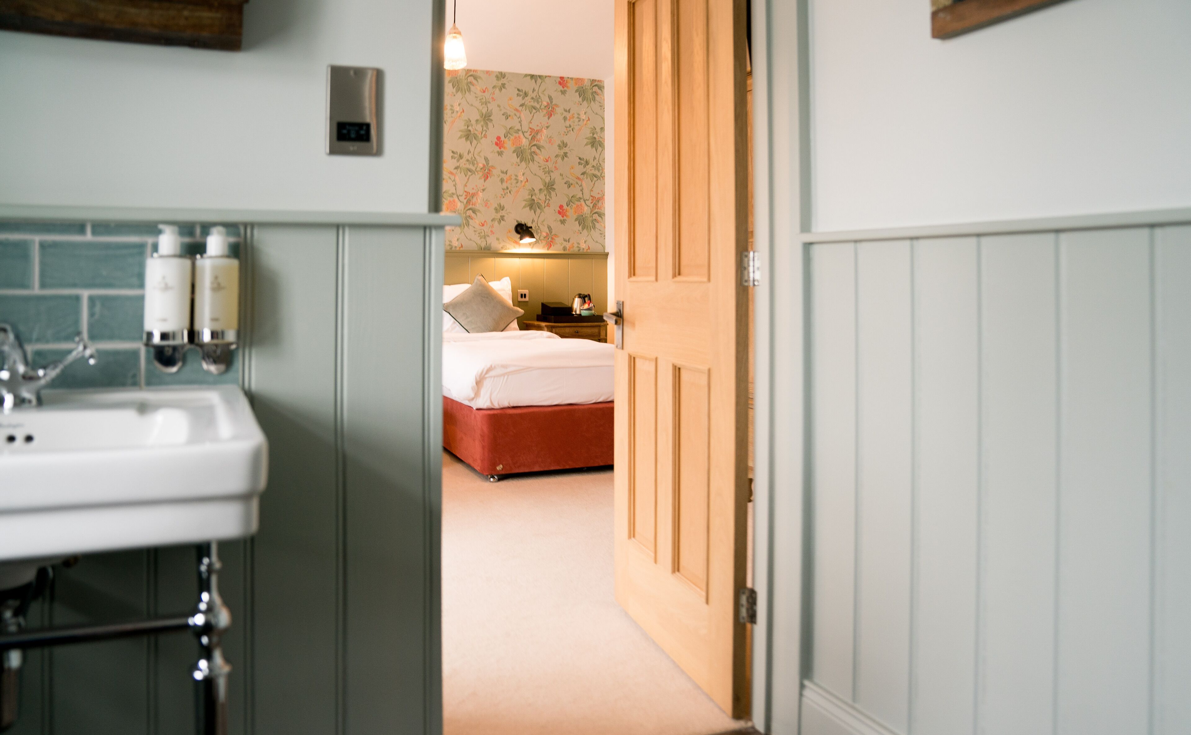 Una habitación de hotel con baño, una cama y una mesita de noche.