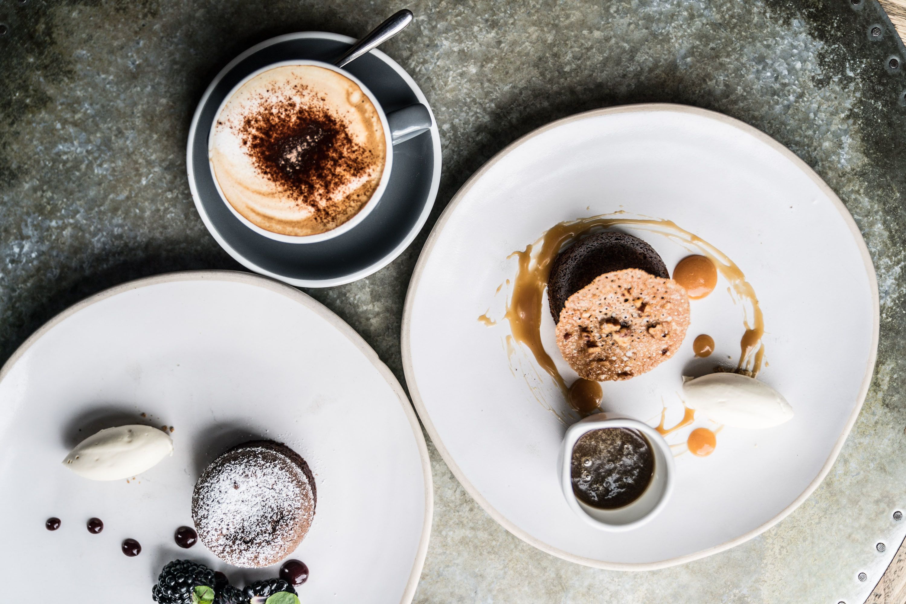 A dessert plate with a chocolate cake, caramel sauce, and berries.