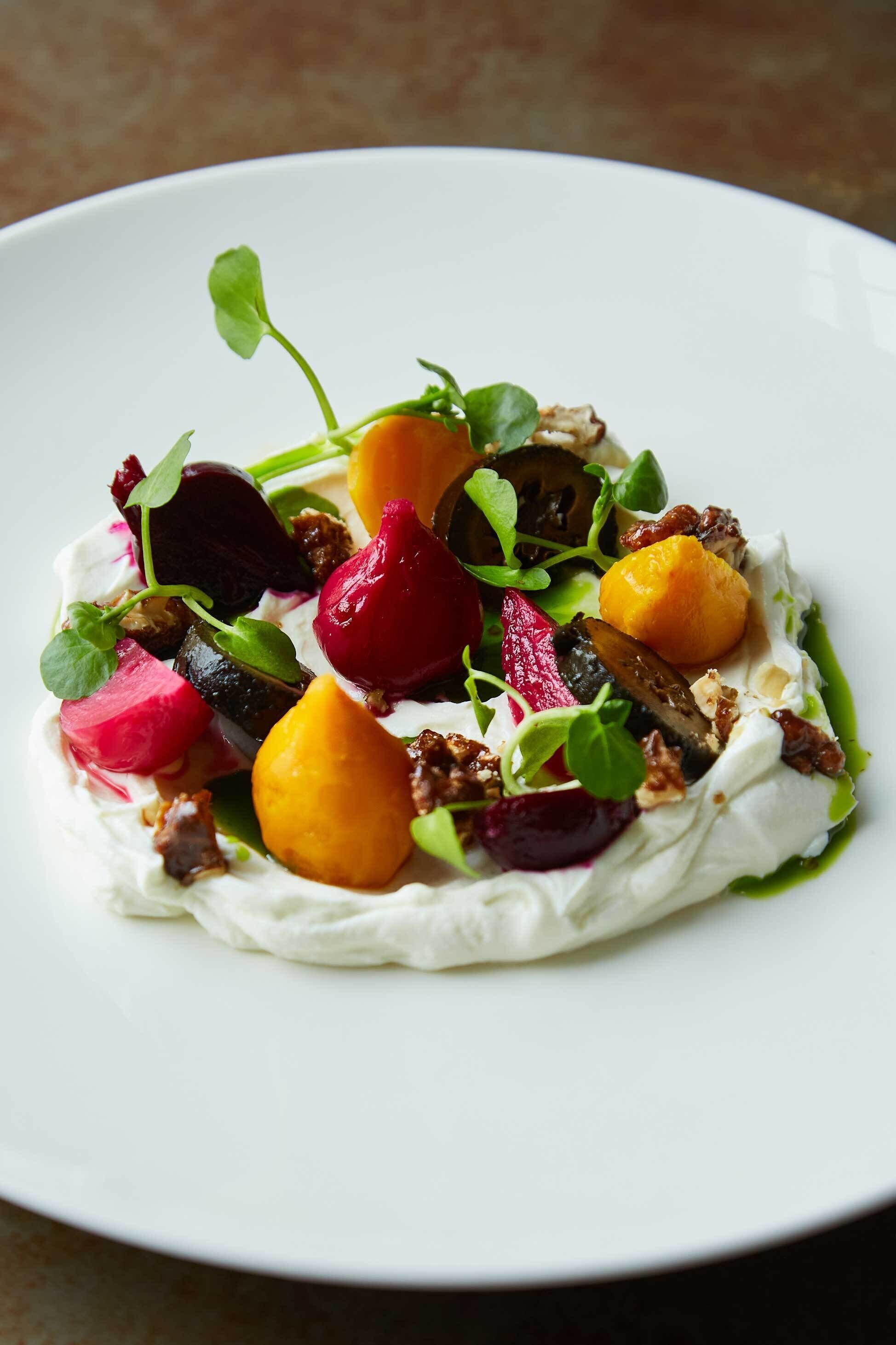 A white plate with a dessert featuring various fruits and greens.