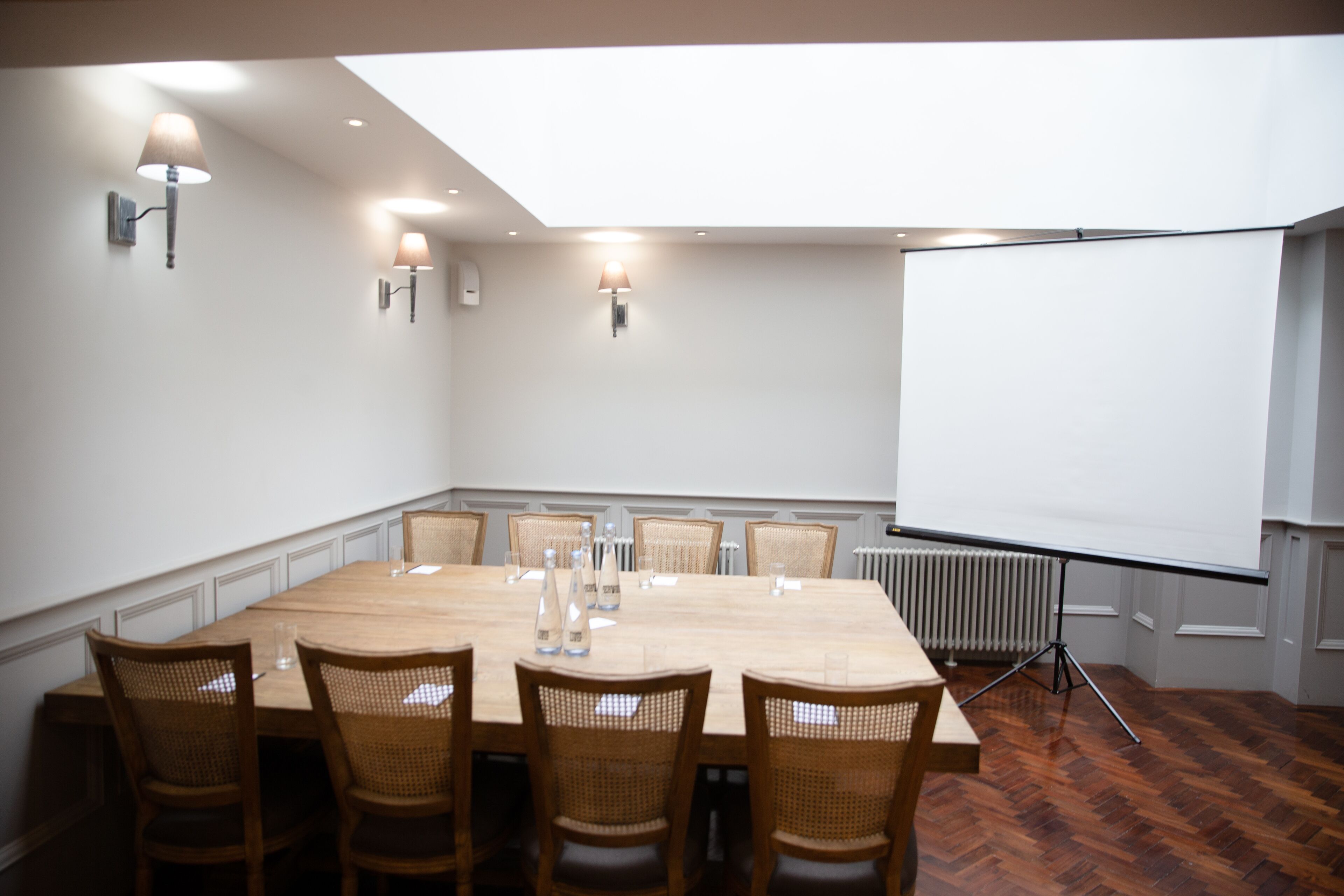A conference room with a large table, six chairs, and a projector screen.
