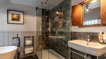 A modern bathroom with a glass-enclosed shower, a white sink, and a framed picture on the wall.