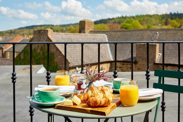 Desayuno en un balcón con croissants, zumo de naranja y café.