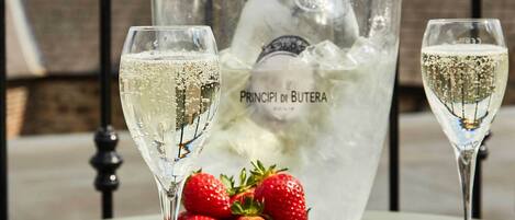 A table with two champagne glasses, a bottle of champagne, and a bowl of strawberries.