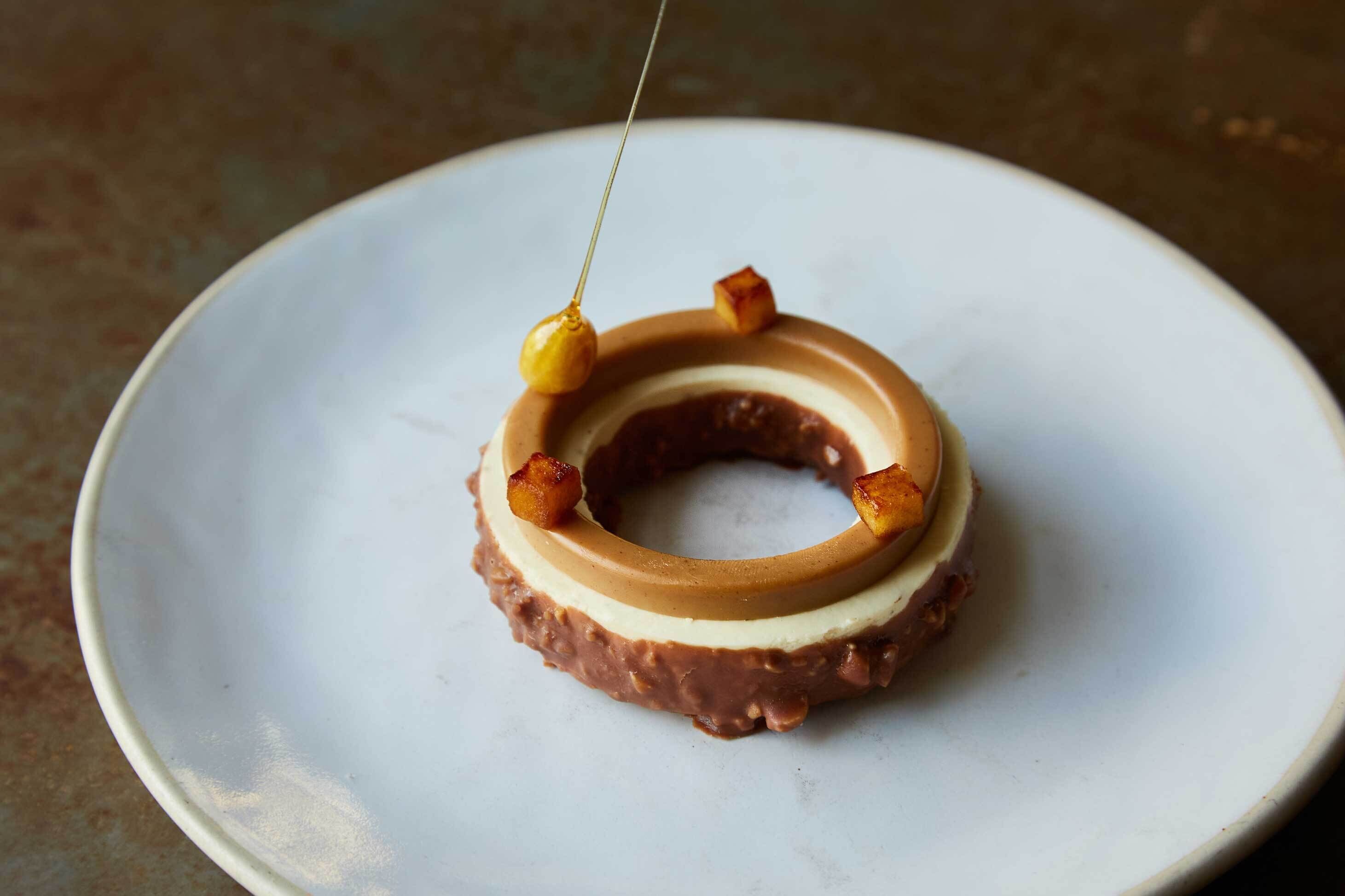 En munk med karamell- och chokladlager, serverad på en vit tallrik.