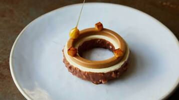 En munk med karamell- och chokladlager, serverad på en vit tallrik.