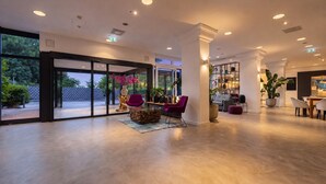 Eine großzügige Lobby mit modernem Design, ausgestattet mit einer Sitzecke, Stühlen, einem Couchtisch und einem Blumentopf.