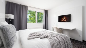 Ein Hotelzimmer mit Bett, Kamin, Fernseher und einem Fenster mit Vorhängen.