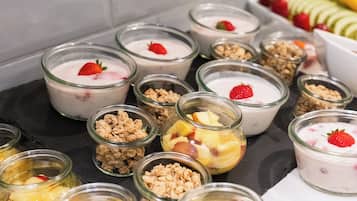 Diverse etenswaren in glazen verpakkingen, waaronder yoghurt met fruit en granola.