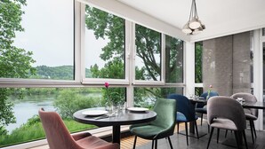 Ein Essbereich mit großen Fenstern, einem runden Tisch und modernen Stühlen.