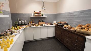 A kitchen with a breakfast buffet, including fruits, cereals, and pastries.