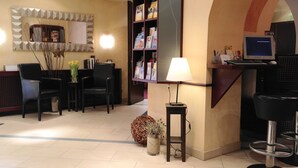 A reception area with a desk, chairs, a computer, and a bookshelf. - Hotel Jensen (Lübeck)
