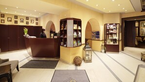 A hotel reception area with a reception desk, a bookshelf, and a seating area with a rug labeled "RINGHOTELS". - Hotel Jensen (Lübeck)