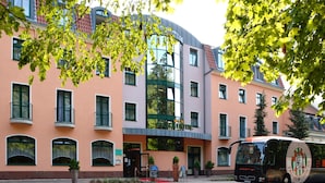A multi-story building with a curved facade, large windows, and a bus parked in front. - Brandiser Parkhotel (Brandis)