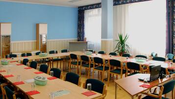 Une salle de conférence équipée de plusieurs tables, de chaises et d’un ordinateur portable posé sur l’une des tables.