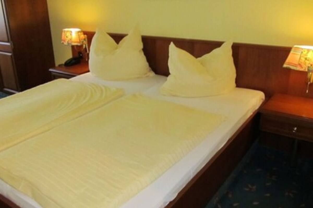A hotel room with a large bed, two bedside tables, and lamps.