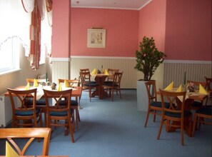 A dining area with wooden tables and chairs, a potted plant, and a framed picture on the wall. - Brandiser Parkhotel (Brandis)