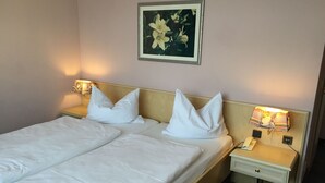 A double bed with white linens, two bedside tables with lamps, a telephone, and a painting of flowers on the wall. - Brandiser Parkhotel (Brandis)