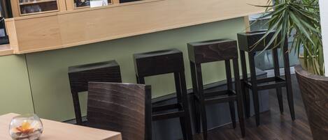 Ein Restaurantinneres mit Holzanbau, Barhocker und einer Topfpflanze.