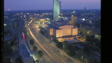A cityscape at dusk with a prominent modern building, wide roads, and a mix of commercial and institutional buildings.