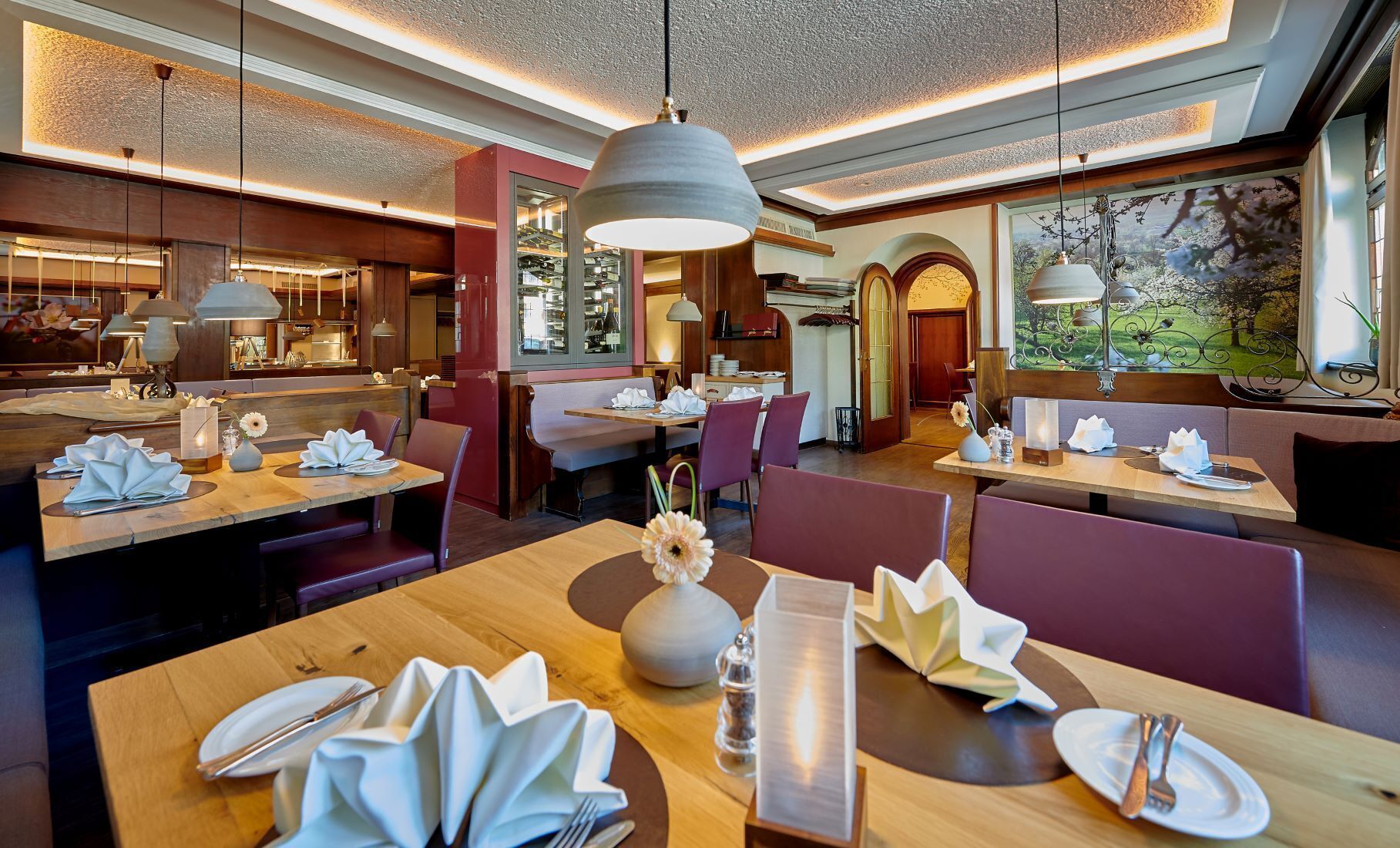 Un restaurante con mesas de madera, sillas moradas e iluminación colgante.