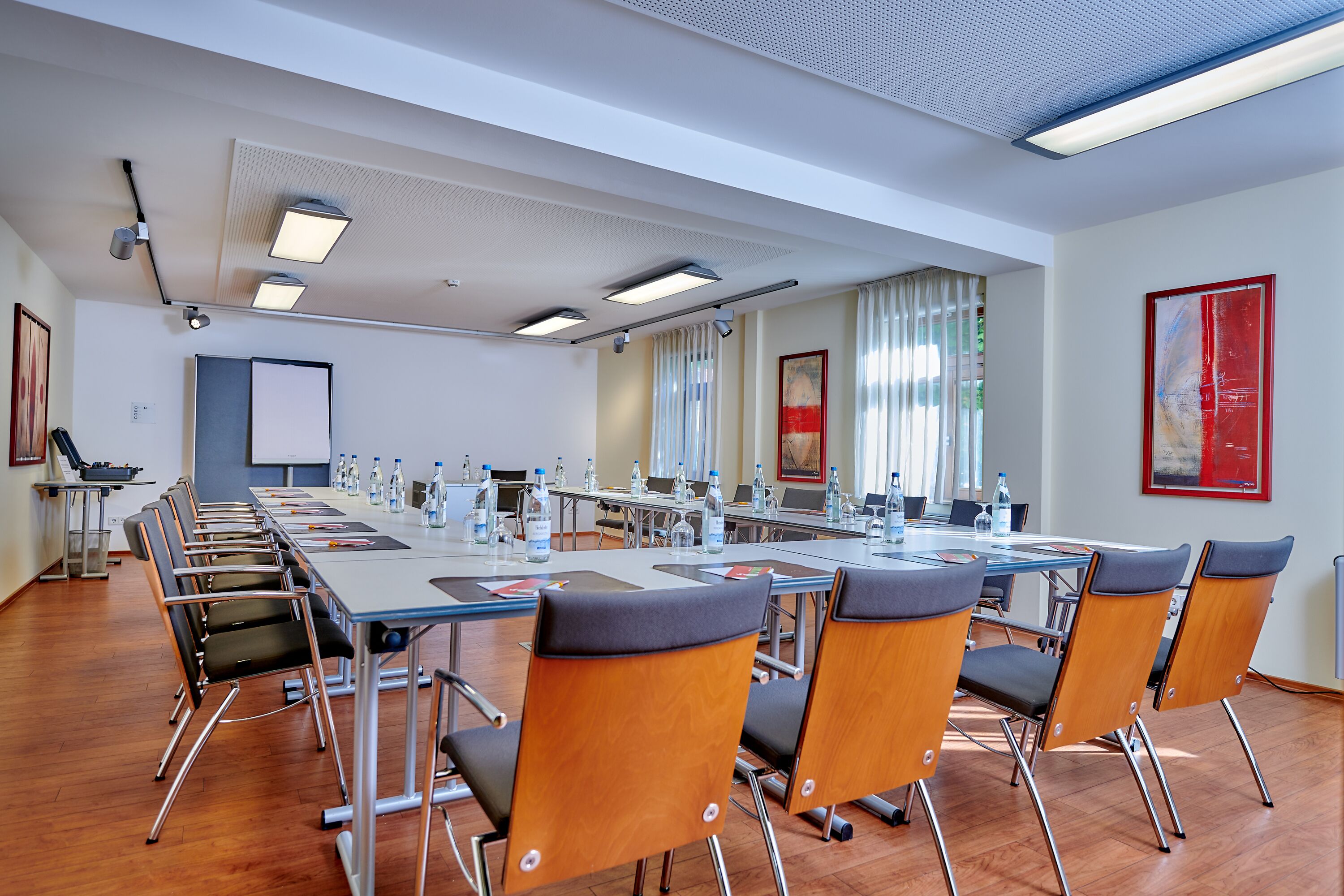 Un salón de conferencias con una larga mesa, sillas y una pantalla para proyector.