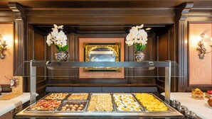 A buffet with various food items, including eggs, meats, and pastries, in a room with wooden paneling and decorative lighting.