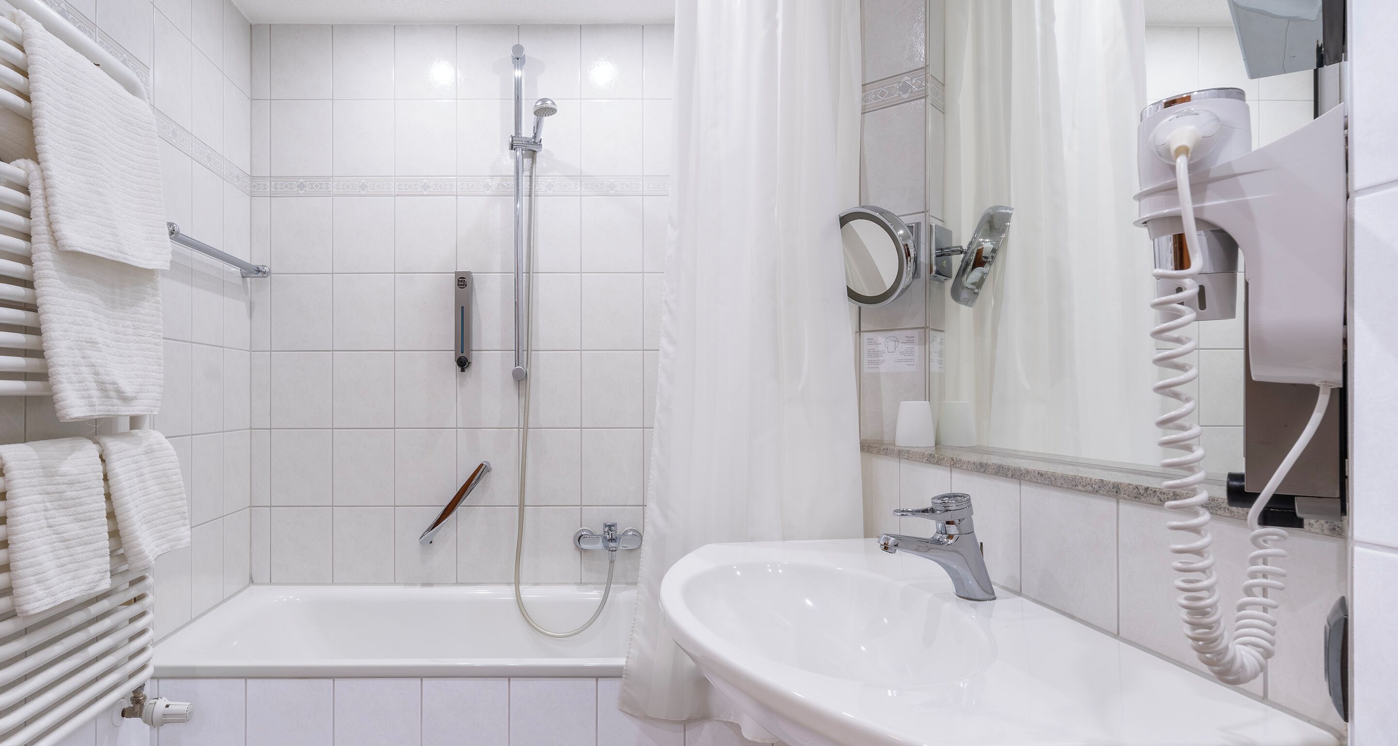 Un baño con bañera, ducha, lavabo y secador de pelo.