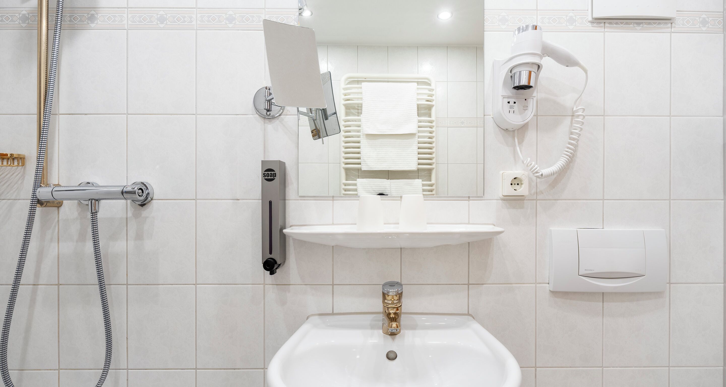 Ein Badezimmer mit Waschbecken, Spiegel, Handtuchhalter und einem Fön.