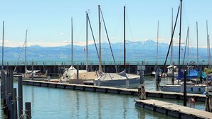 A marina with boats docked, a covered area, and mountains in the background.