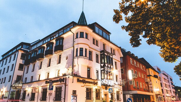 A multi-story hotel with a prominent corner turret, a ground-level bar, and a visible parking sign.