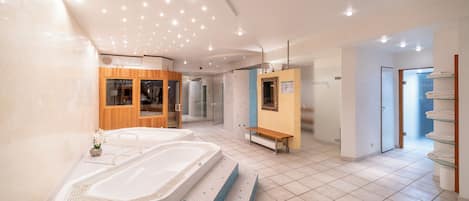 Un espace spa moderne comprenant deux grandes baignoires, un meuble en bois, un banc et une cabine de douche en verre.
