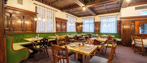 Una posada tradicional con muebles de madera, asientos tapizados en verde y una alfombra estampada.