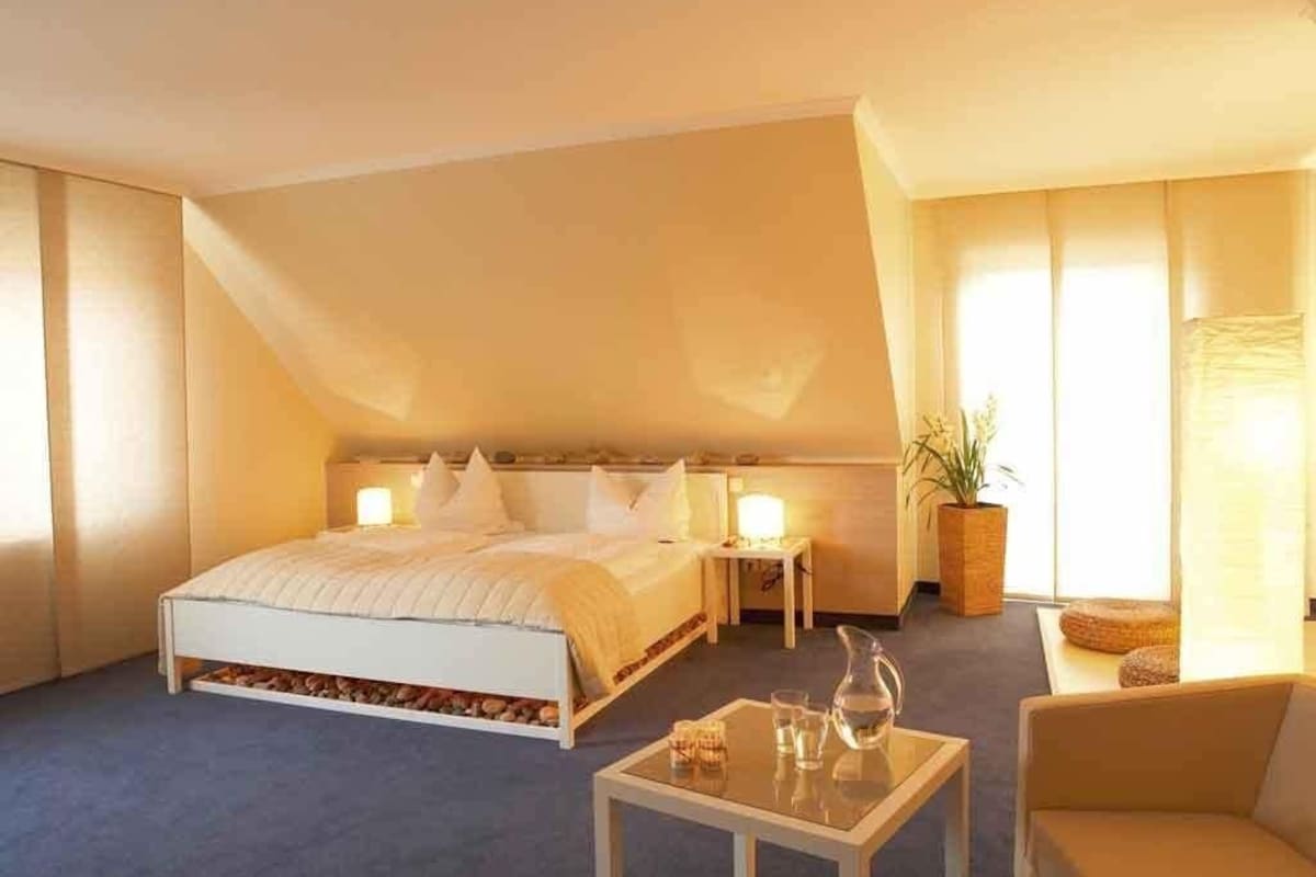 A bedroom with a bed, bedside tables, a coffee table, and a sofa.