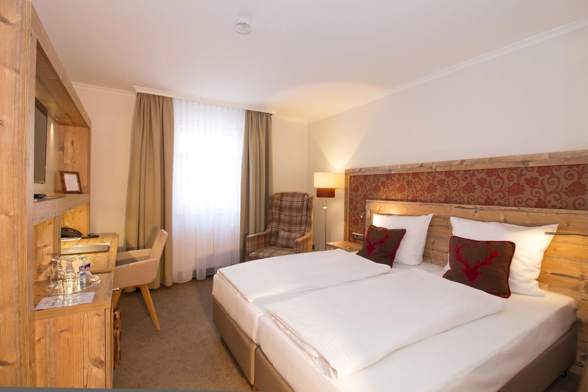 Une chambre d’hôtel avec un lit double, un bureau avec une chaise, un téléphone et une lampe.