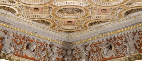 Techo con decoraciones ornamentales en dorado y blanco, incluyendo medallones circulares y esculturas en relieve.