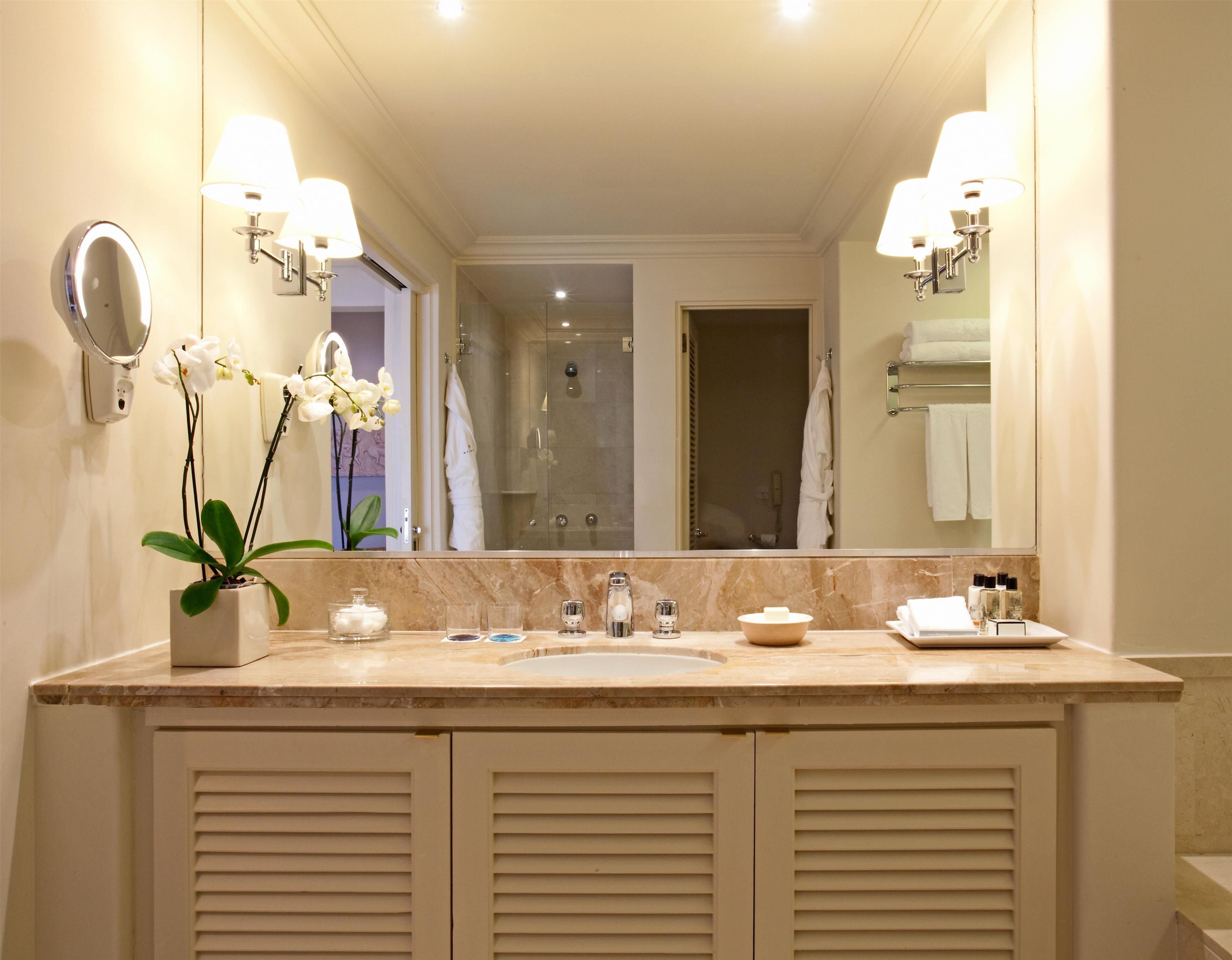 A bathroom with a double sink vanity, a large mirror, and a potted orchid.