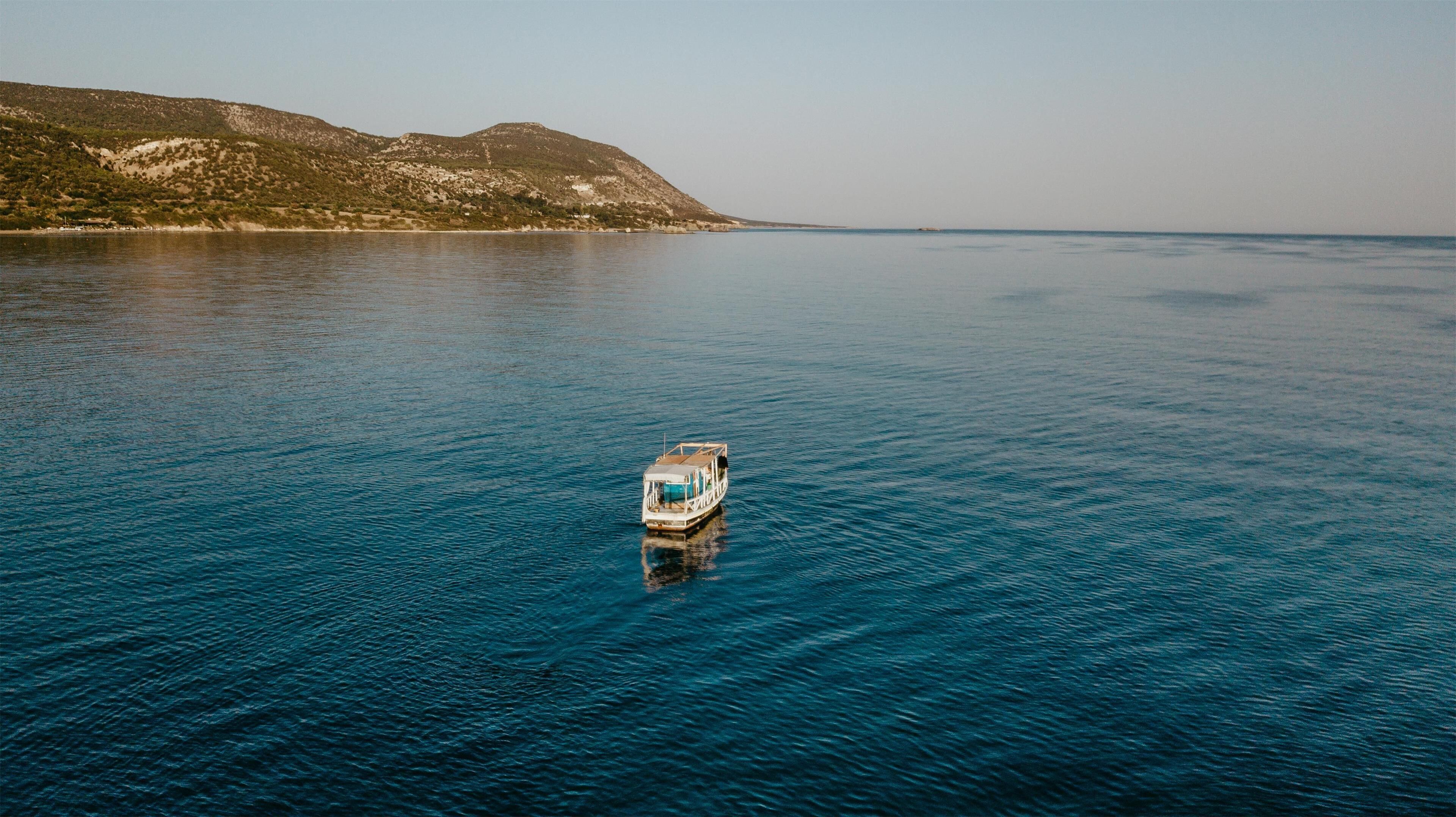Un bote sobre aguas tranquilas con un paisaje montañoso al fondo.