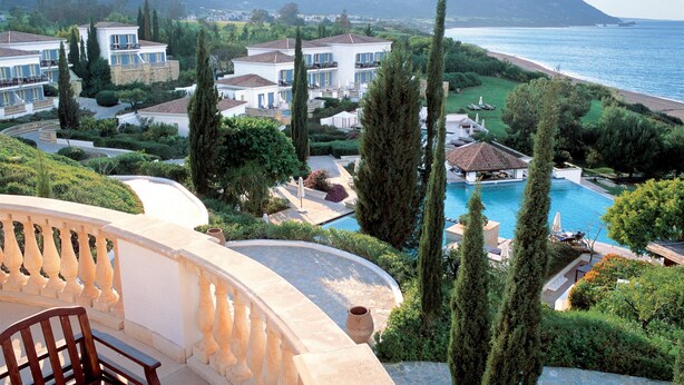 Un complejo turístico costero con varias villas, una piscina y vista al mar.