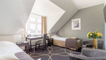 Et hotelværelse med seng, skrivebord, stol og en lille sofa.