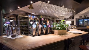 Un espace bar doté de plusieurs tireuses à bière, d’un comptoir en bois et d’une variété de bouteilles et de verres.